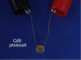LED photocell, two alligator clips holding wires connected to unlit LED bulb