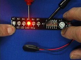 LED strip with 6 bulbs. One lit up orange in the the middle, held in hand