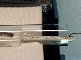 small glass test tube on its side with metal hook pulling substance through opening