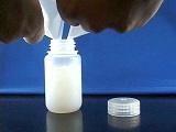 hand scraping Zeolite sample into small plastic bottle