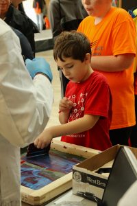 A child screen prints at the WI Science Festival