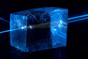 Fluorescence in calcite crystal and birefringence as laser beam splits in two while traveling from left to right