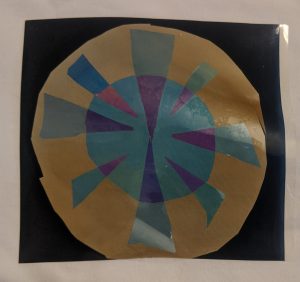 Cellophane layered to create a circle with geometric shapes inside when viewed through polarizers